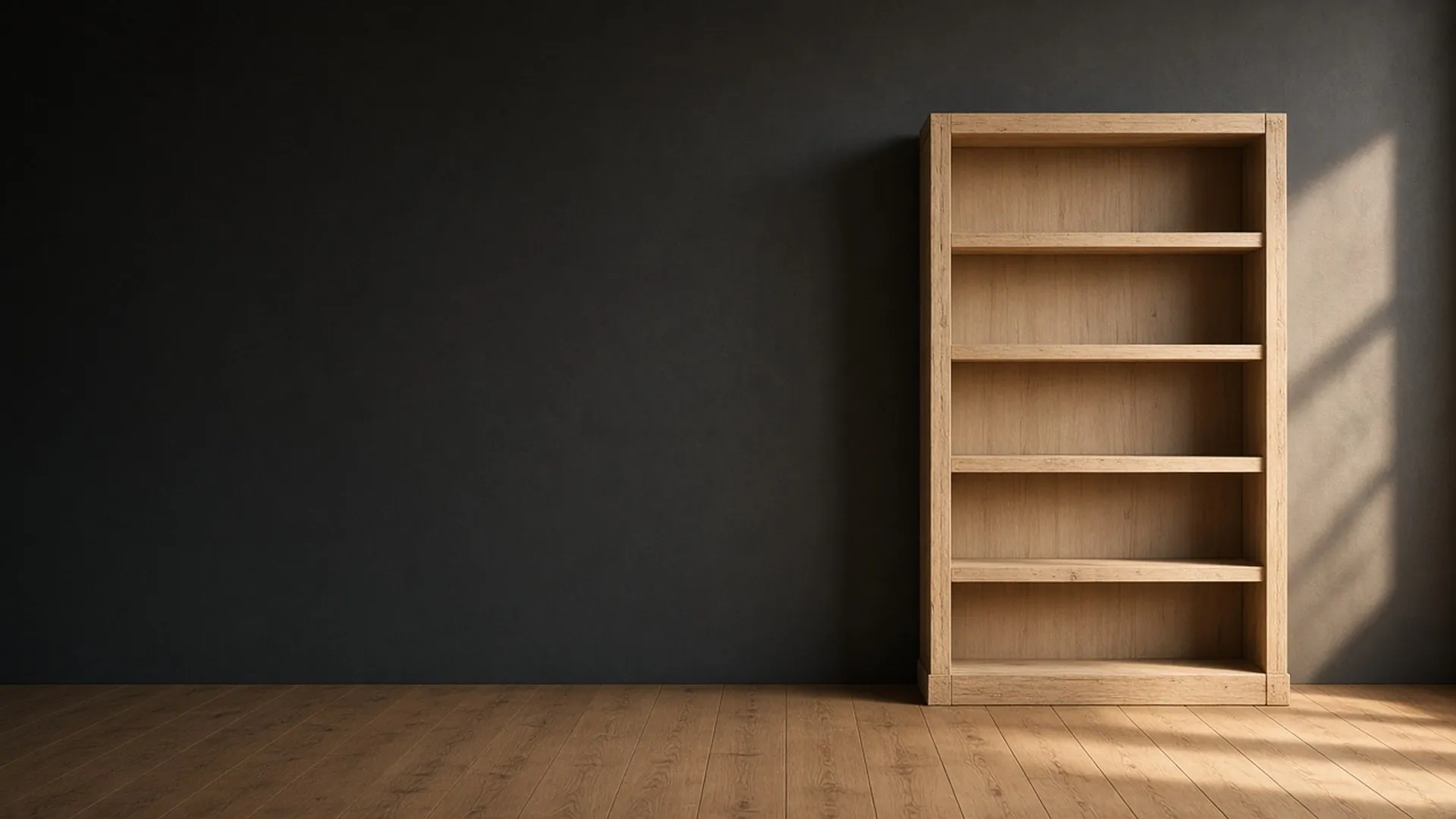 An empty bare wood bookcase with open shelves standing against a dark charcoal wall