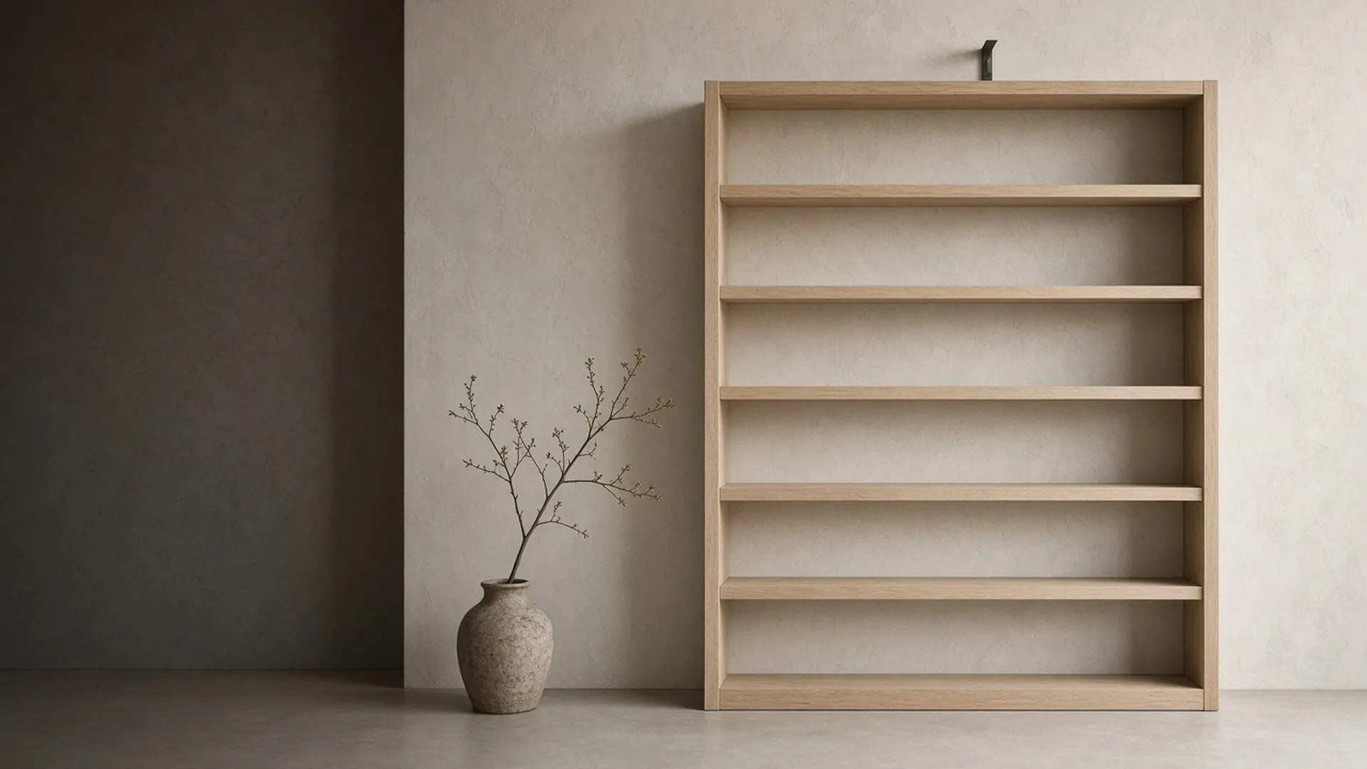 A tall empty bare wood bookcase flat against a pale wall with a bracket fitted