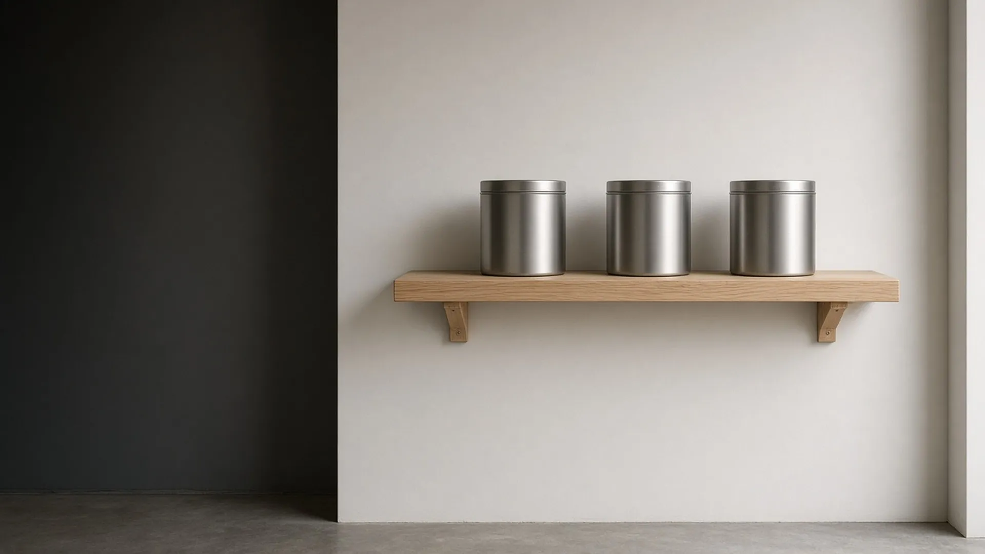 Three closed unlabeled metal tins on a high shelf in a tidy garage