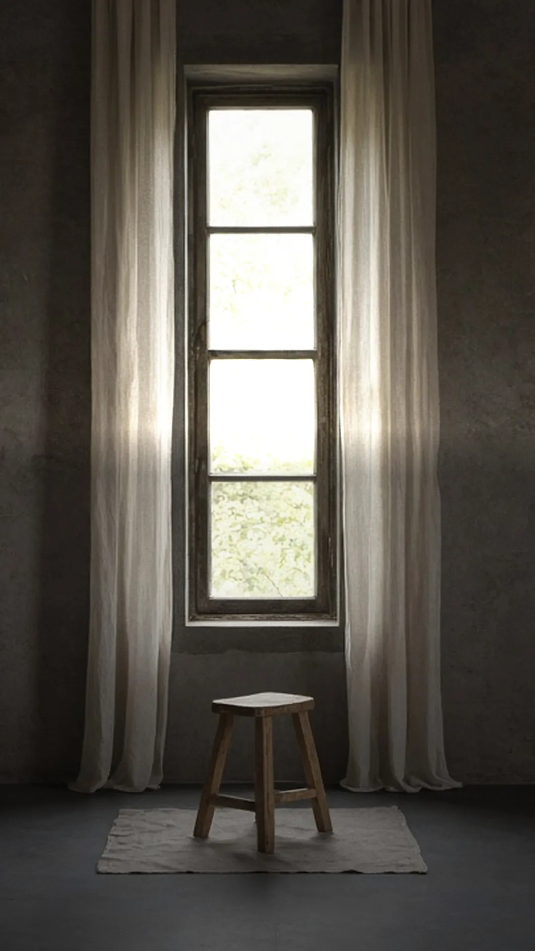A bare wood stool on a plain drop cloth below a tall window between sheer curtains