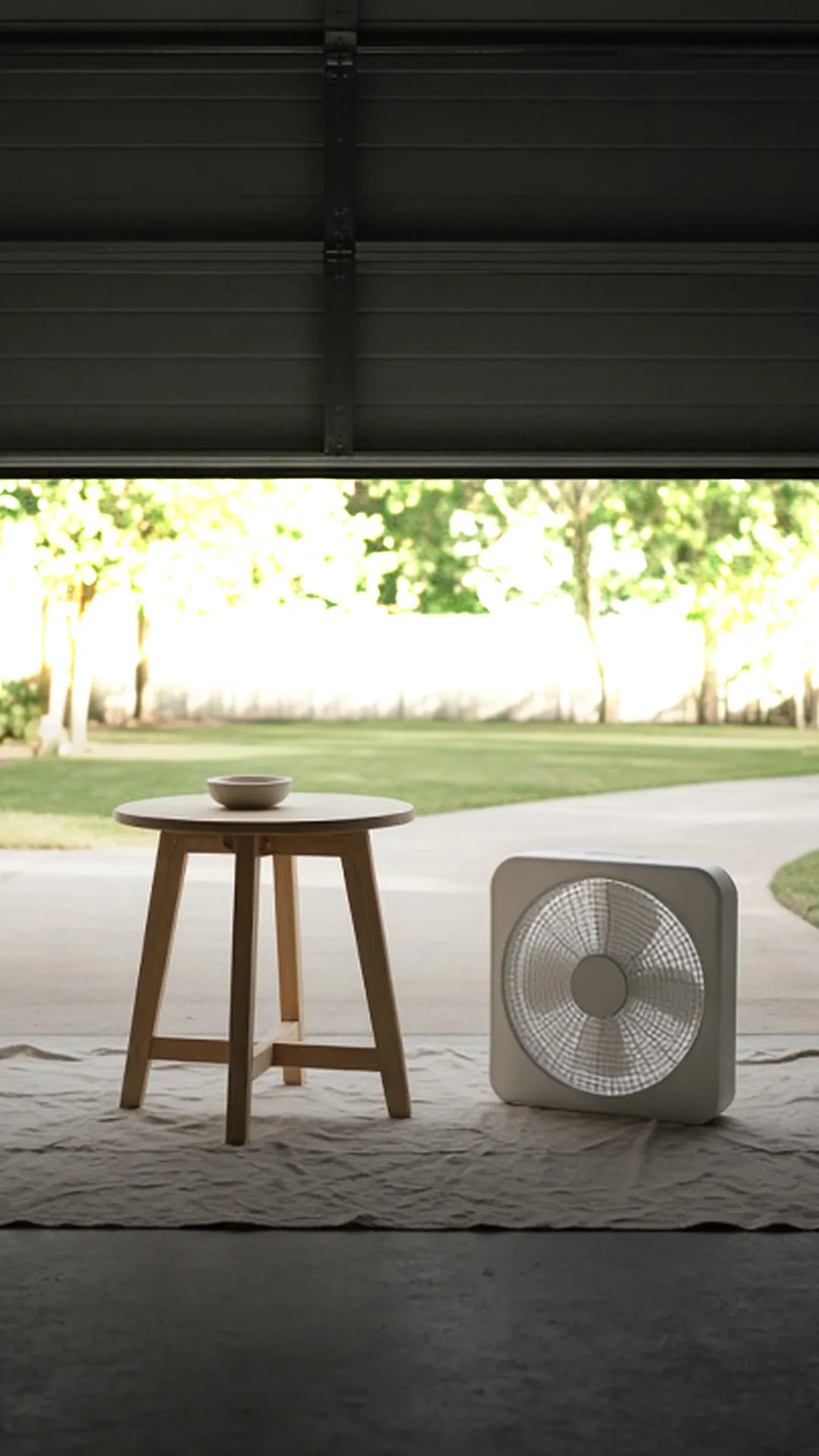 A bare wood side table on a drop cloth inside an open garage door